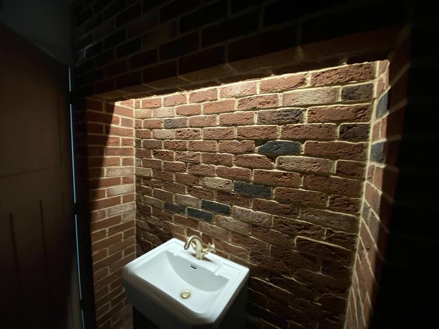 Finished bathroom with exposed brick feature and lighting